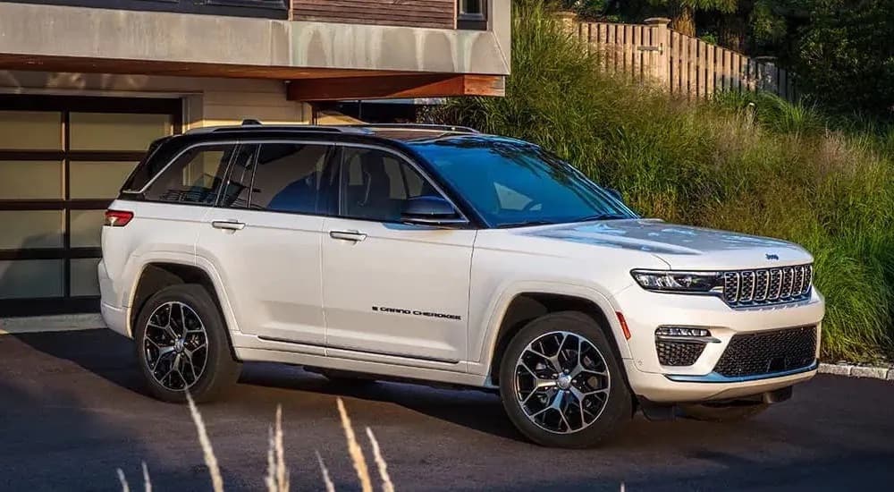A white 2022 Jeep Grand Cherokee is shown from the side on a driveway.